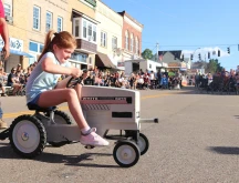 A girl at the fredericktown tomato show on a mini tractor.