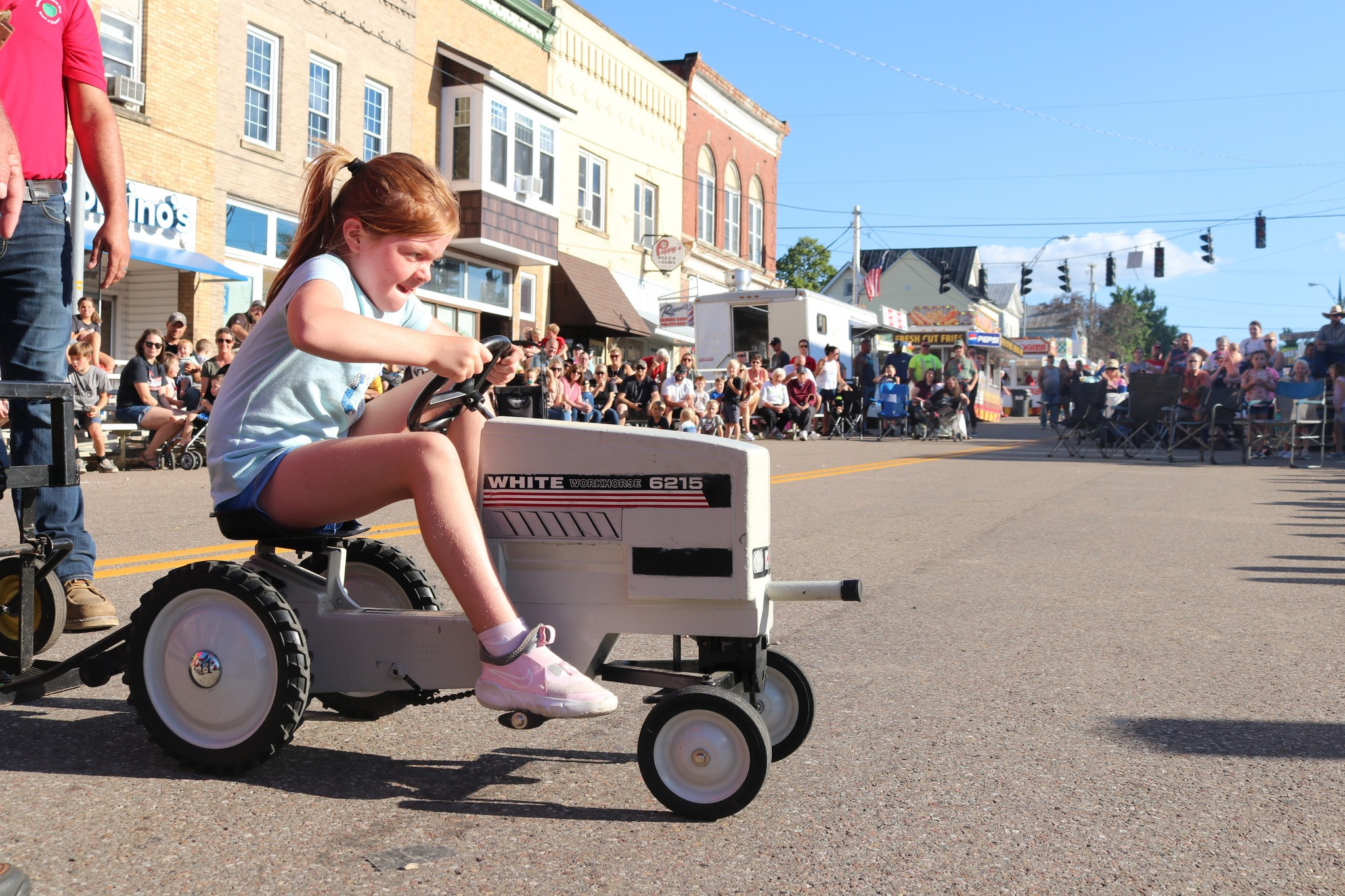 A girl at the Fredericktown tomato show riding a mini tractor.
